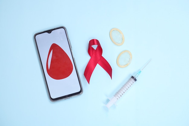 Simbolo del nastro rosso e del dispositivo medico contro il virus hiv isolato su sfondo blu Foto Premium