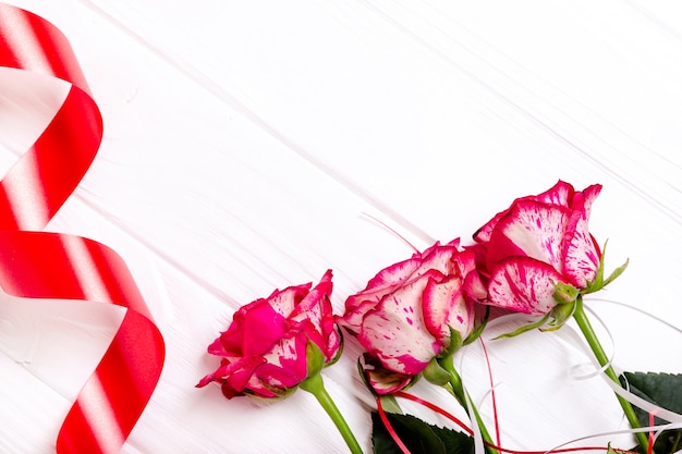 Red ribbon and roses isolated on white background