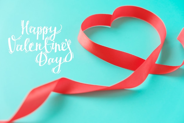 Red ribbon in the shape of a heart on a mint background