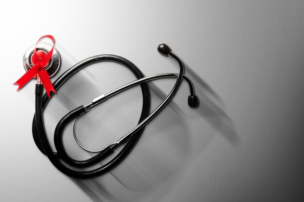 Red ribbon and stethoscope with white background. Hiv Aids ribbon awareness