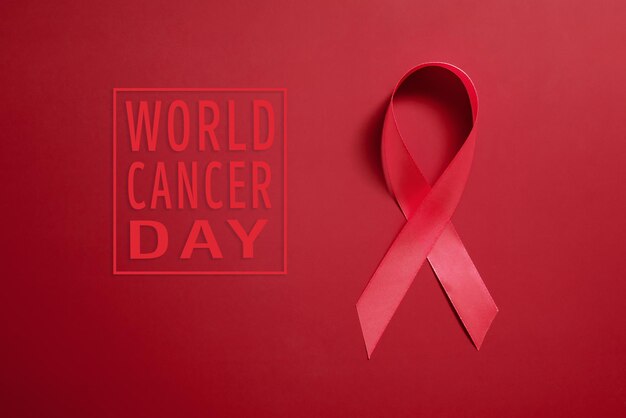 Red ribbon symbol of world aids day on red background copy space