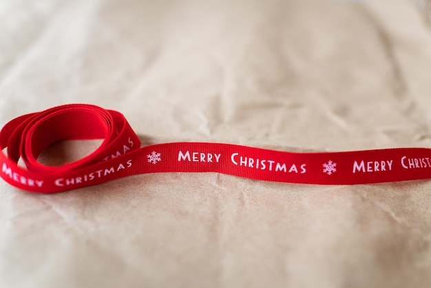 Red ribbon with the inscription Merry Christmas spread out on craft paper Place for an inscription