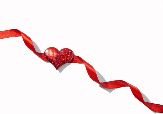 Red ribbon with shiny red heart isolated on white background