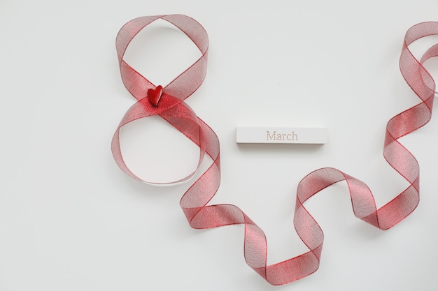 Red ribbon and word MARCH on white background. 8 March, International Women's Day concept.