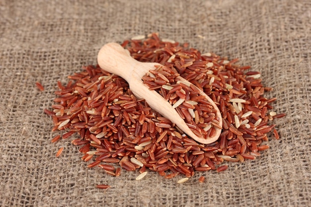 Photo red rice on sacking in wooden scoop