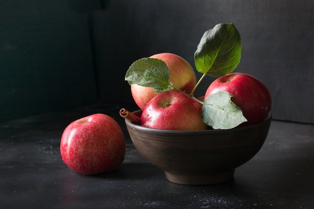 Red ripe apple in vase on dark.