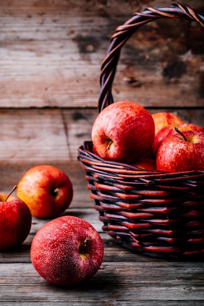 Red ripe apples in a basket on a wooden rustic background