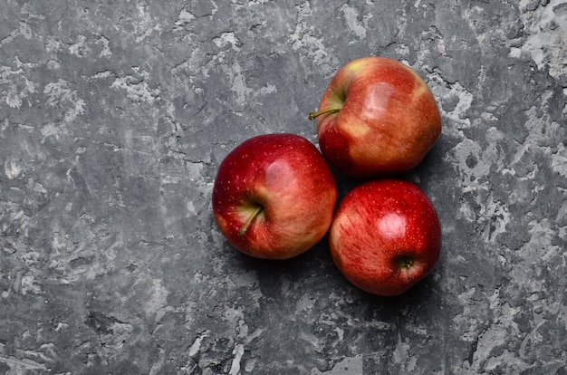 Красные спелые яблоки на бетонном столе. Свежие фрукты. Лофт и деревенский стиль. Вид сверху
