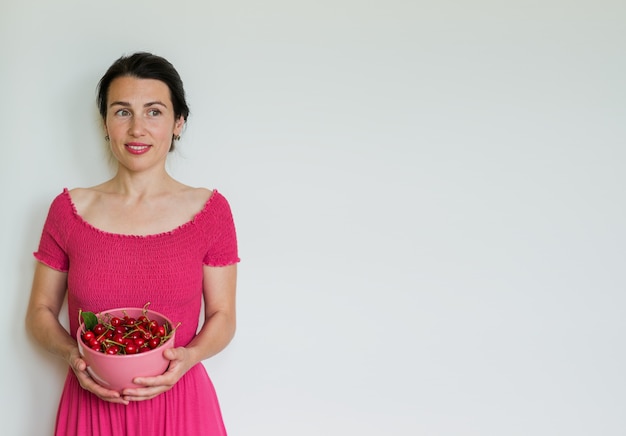 Red ripe cherries in bowl in hands of woman. Healthy eating, vegetarian food and diet people concept