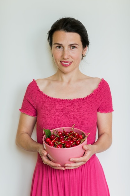 Red ripe cherries in bowl in hands of woman. Healthy eating, vegetarian food and diet people concept