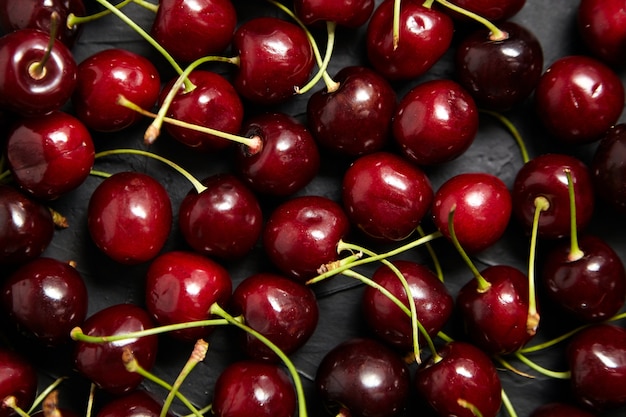 Red ripe cherries scattered on a black table