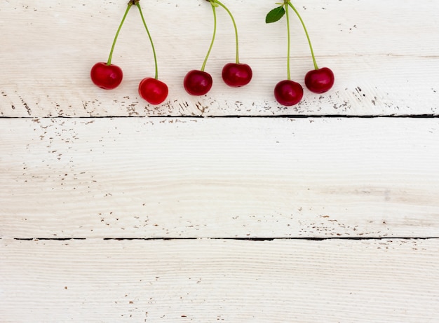 Photo red ripe cherries on top of the white horizontal boards.