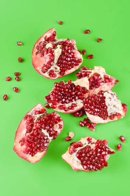 Red ripe fresh juicy sliced pomegranate isolated on green background