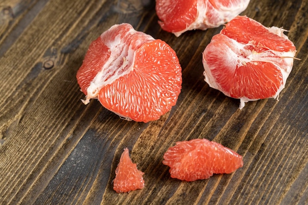 Красный спелый грейпфрут на разделочной доске, очищенный до мякоти спелого красного грейпфрута