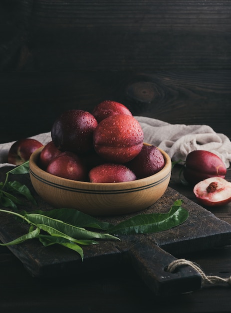 Red ripe peaches nectarine in a wooden plate, close up