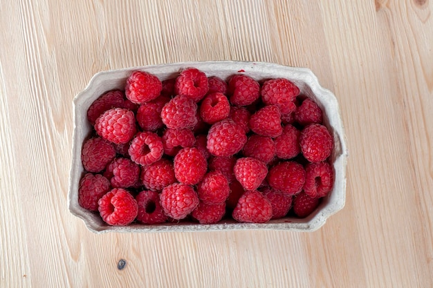 Red ripe raspberries in a package harvested red ripe raspberries on the table