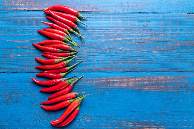 Photo red ripe small chili peppers pattern over old wooden blue background in flat lay.