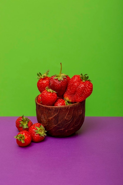 Red ripe strawberries in a cup on a colored background