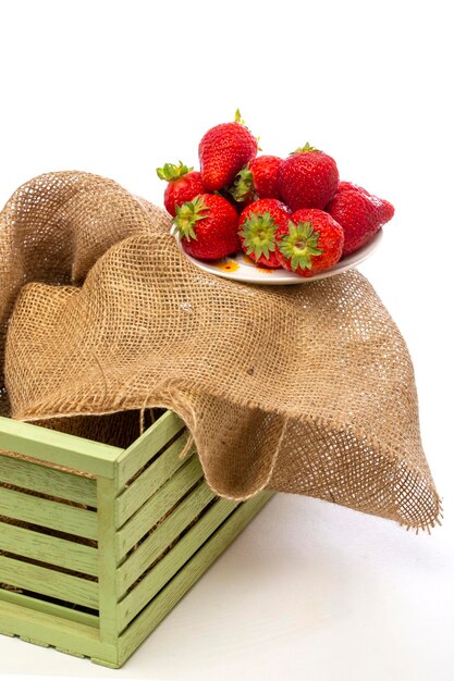 Red ripe strawberries in a plate on a burlap