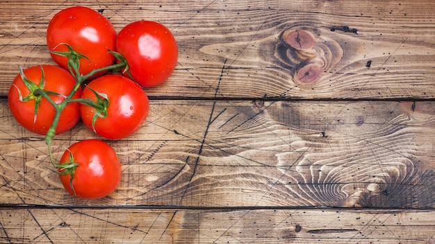 Red ripe tomatoes on a branch. Wooden background .