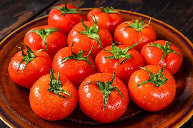 Red ripe tomatoes on rustic plate