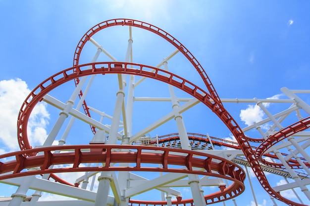 Red roller coaster rail in bright blue sky