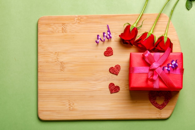 Red rose bunch and gift box on wooden board. Valentine day concept