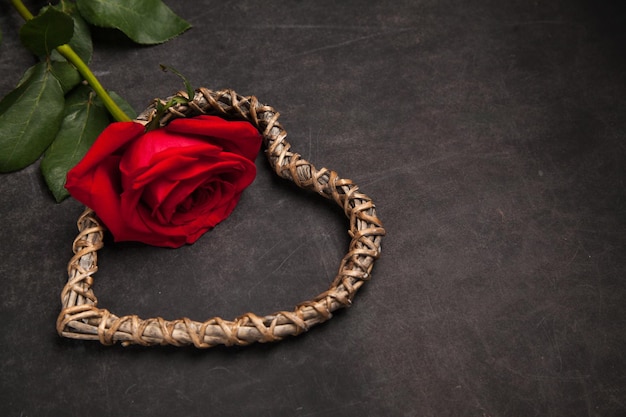 Rosa rossa su sfondo scuro con concetto di relazione romantica in legno a forma di cuore