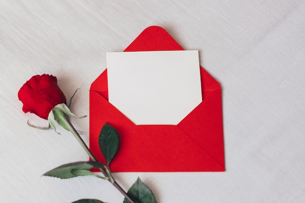 Red rose and envelope with copy space laying on white bed Valentines day love and romance