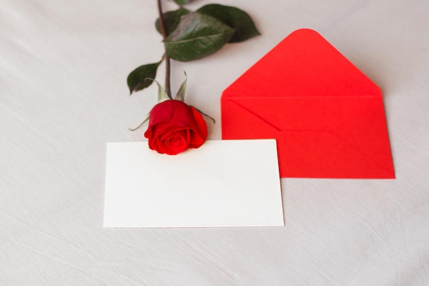 Red rose and envelope with copy space on white bed background