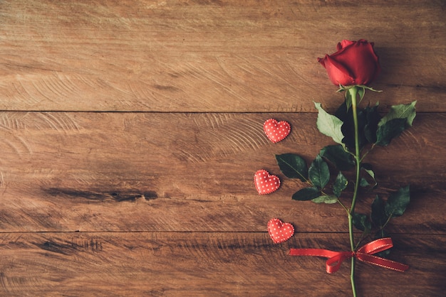 Красная роза и маленькое сердце на деревянном полу