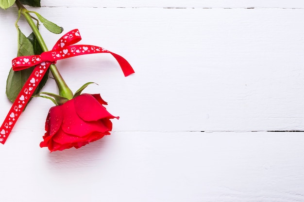 白い木製の背景に愛の赤いバラ