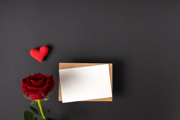 A red rose and a mockup of a kraft envelope with a blank sheet on a black background Banner for Valentine's Day Postcard for February 14 Love Minimalism