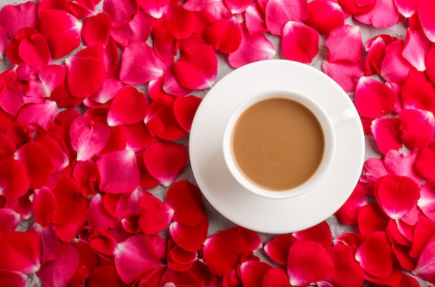 Red rose petals background and a cup of coffee.