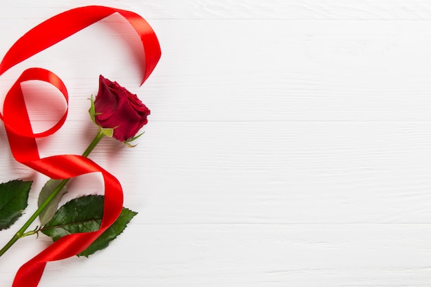 Red rose, ribbon on the white table.