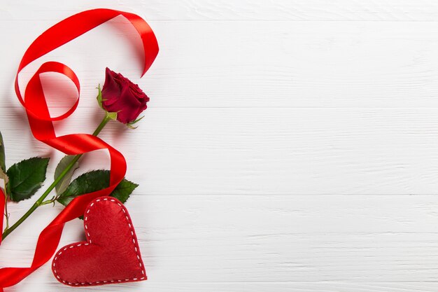 Red rose, ribbonnd heart on the white table.