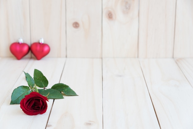 Photo red rose and two hearts on wooden background