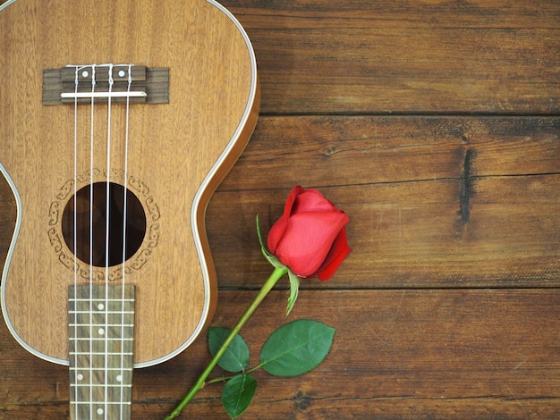 Foto rosa rossa e ukulele su fondo di legno per la carta di san valentino.