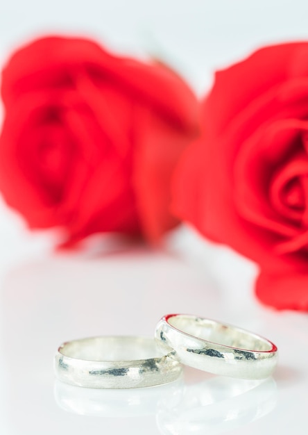 Foto rosa rossa e anello di nozze su bianco