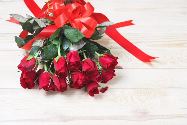 Red rose with red ribbon on wood background with copy space.