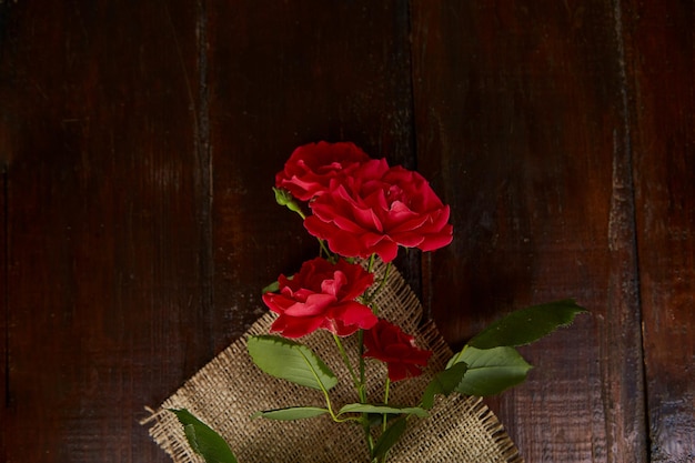 Red roses background on sacking on wooden background Present gifting Copy space