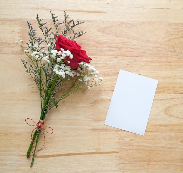 Red roses flower bouquet and blank white note paper on wood background