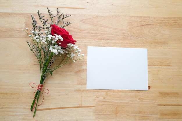 Red roses flower bouquet and blank white note paper on wood background