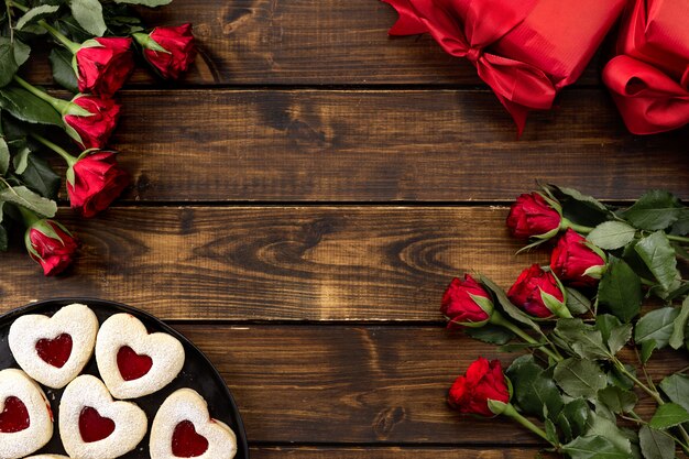 Red roses, gift boxes, linzer cookies on a dark wooden 