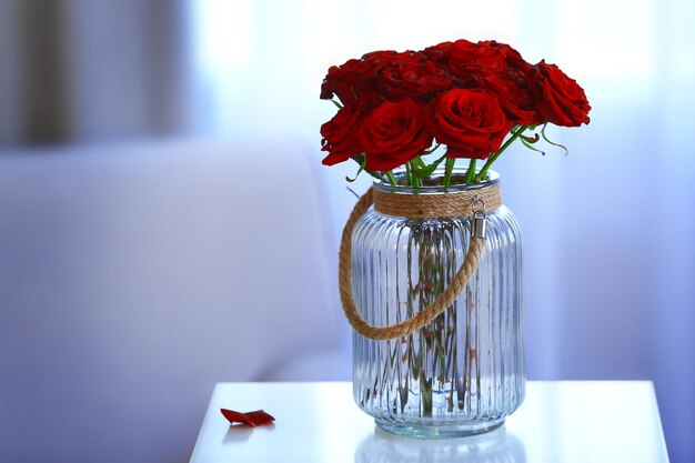 Red roses in a glass jar in the room