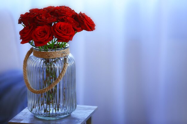 Red roses in a glass jar in the room