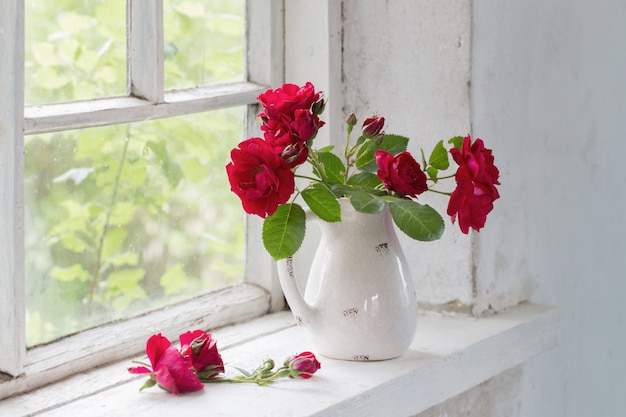 Red roses in jug on winwowsill