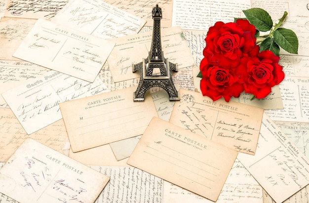 Rose rosse, vecchie lettere e souvenir torre eiffel da parigi. sfondo di vacanze nostalgiche