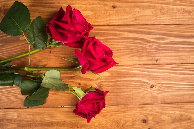 写真 木製の表面に赤いバラ