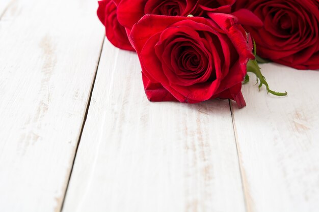 Red roses on white wooden surface